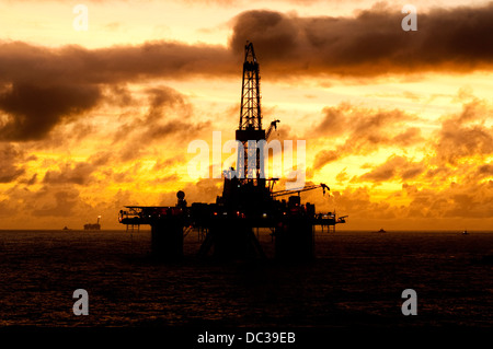 Silhouette von einer Offshore-Bohrinsel fern am Horizont zu Sonnenaufgang/Sonnenuntergang Zeit. Stockfoto