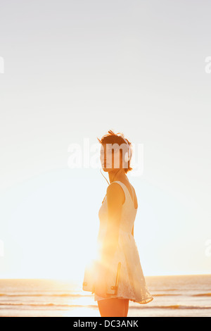 Frau im Kleid tragen Kopfhörer am Sonnenstrand Stockfoto