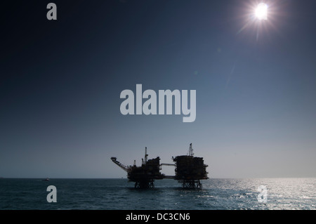 Silhouette einer Bohrinsel im Offshore-Bereich, harte Gegenlicht, blauen Himmel, Refelection auf der Wasseroberfläche. Stockfoto