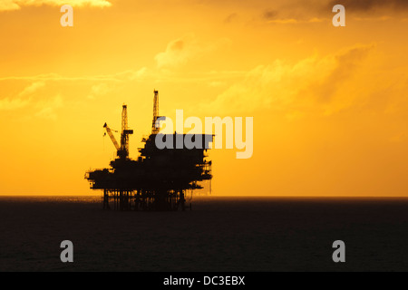 Silhouette von einer Offshore-Bohrinsel fern am Horizont zu Sonnenaufgang/Sonnenuntergang Zeit. Stockfoto