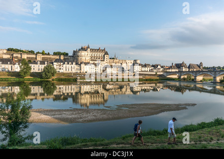 Panorama des Königlichen Schlosses, andere in der Nähe gelegene Gebäude und die Brücke, alle gespiegelten im Fluss Loire, mit zwei Personen zu Fuß durch. Amboise, Frankreich. Stockfoto