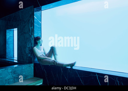 Frau sitzt auf der Fensterbank und Blick auf Unterwasser-Blick auf pool Stockfoto