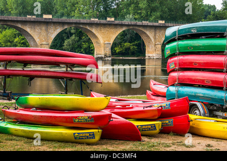 Bunte Kanus zu mieten in der Nähe einer Brücke gestapelt auf dem Fluss in Limeuil, wo die Flüsse Dordogne und Vézère, South West France. Stockfoto