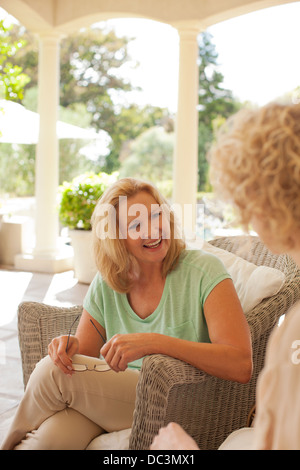 Lächelnde Mutter und Tochter sprechen auf Veranda Stockfoto