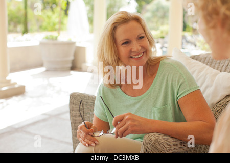 Lächelnde Mutter und Tochter sprechen auf Veranda Stockfoto