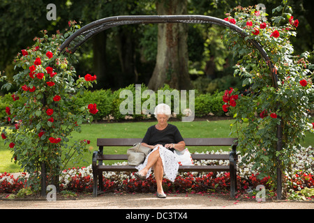 Ältere Dame sitzt in Hall Leys Park, Zentrum Matlock, Derbyshire, UK Stockfoto