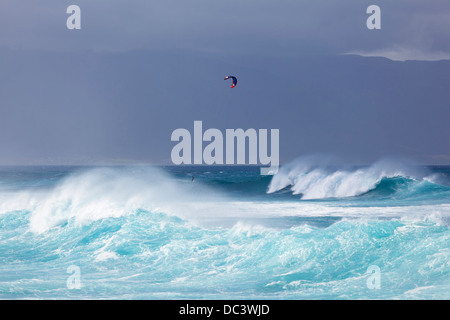 Hohe Wellen an der Nordküste Mauis mit Kitesurfer im Hintergrund. Stockfoto