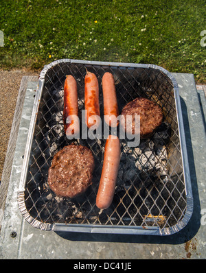 eine Mischung von Würstchen und Burger cookin auf einem Grill Stockfoto