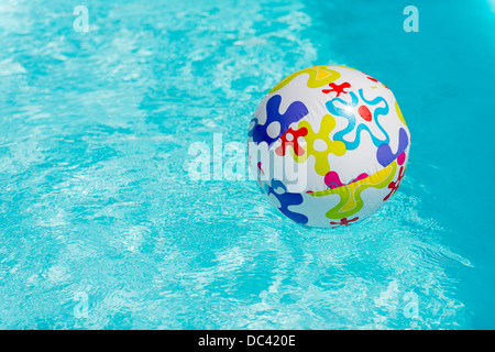 Bunte Beach-Ball schwimmt auf Wasser des Swimmingpools Stockfoto