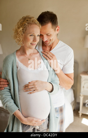 Lächelnde Mann umarmt schwanger Frau Stockfoto