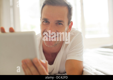 Porträt von lächelnder Mann mit digital-Tablette im Bett Stockfoto