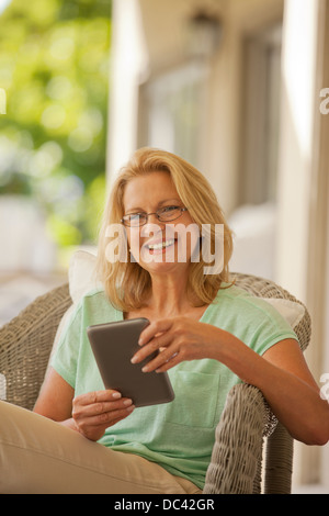 Porträt der lächelnde Frau mit digital-Tablette auf Veranda Stockfoto