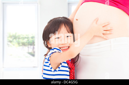 glückliche kleine Mädchen umarmt eine schwangere Mutter Bauch Stockfoto