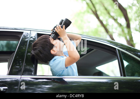 Fröhliche junge aus Autofenster gelehnt und mit dem Fernglas suchen Stockfoto