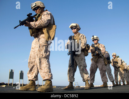 US-Marines stehen in einer Linie, wie sie sich vorbereiten, während ein scharfer Munition-Übung auf dem Flugdeck der USS San Antonio 14. Juli 2013 in das Arabische Meer auf Ziele feuern. Stockfoto