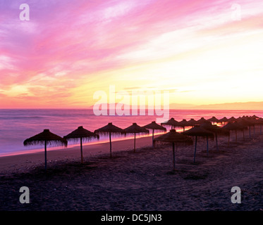 Sonnenschirme am Strand bei Sonnenuntergang, Torrox-Costa, Costa Tropical, der Axarquia, Provinz Malaga, Andalusien, Südspanien, Westeuropa. Stockfoto