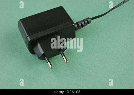 Schwarz-Ladegerät Adapter mit Stecker auf grünem Hintergrund Stockfoto