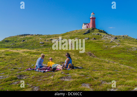 Kanadier, zwei Frauen und ein Mann in den Zwanzigern, Picknick draußen auf dem Boden unterhalb des Leuchtturms Ferryland in Neufundland. Stockfoto