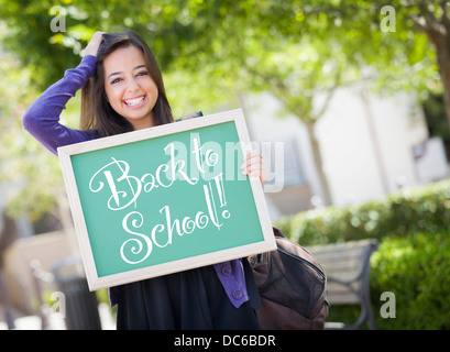 Aufgeregt Mixed Race weibliche Schüler hält eine Tafel mit zurück zu Schule darauf geschrieben. Stockfoto