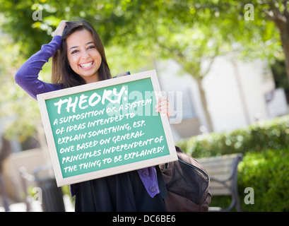 Aufgeregt Mixed Race weibliche Schüler Holding Tafel mit Thoery und die Definition darauf geschrieben. Stockfoto