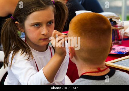 Eine süße junge Mädchen konzentriert sich auf das Gesicht eines jungen Malerei. Stockfoto