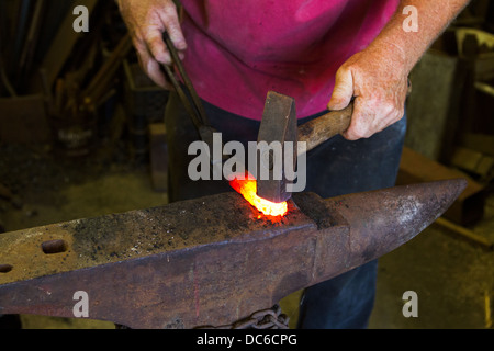 Schmied, weißes heißes Eisen mit Hammer am Amboss zu schlagen. Stockfoto