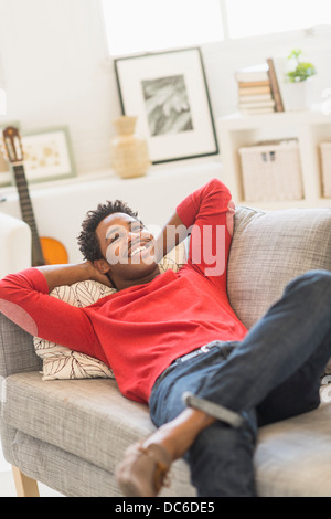 Mann auf dem Sofa liegend und lächelnd Stockfoto
