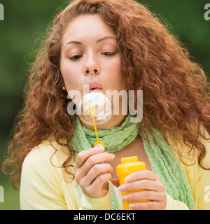 Junge Frau bläst Seifenblasen im park Stockfoto