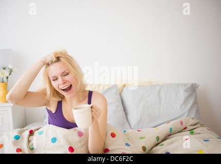 Junge Frau im Bett Gähnen Stockfoto