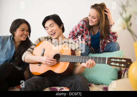 Junge Frauen Mann spielt Gitarre anhören Stockfoto