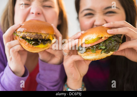 Junge Frauen, die Hamburger essen Stockfoto