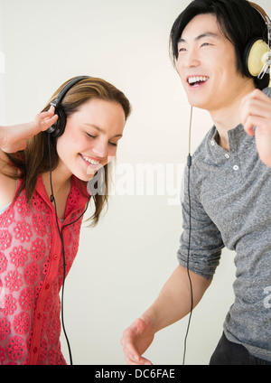 Porträt der jungen Frau und Mann anhören von Musik auf MP3-player Stockfoto
