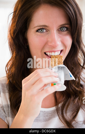 Porträt der jungen Frau Essen Müsliriegel Stockfoto