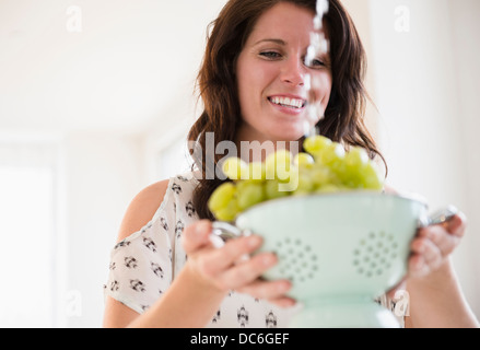 Porträt der jungen Frau, die Trauben im Sieb waschen Stockfoto