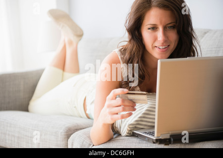 Junge Frau auf Sofa machen Online-shopping Stockfoto