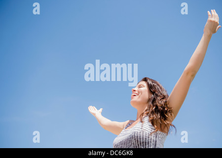 Glückliche Frau gegen blauen Himmel Stockfoto