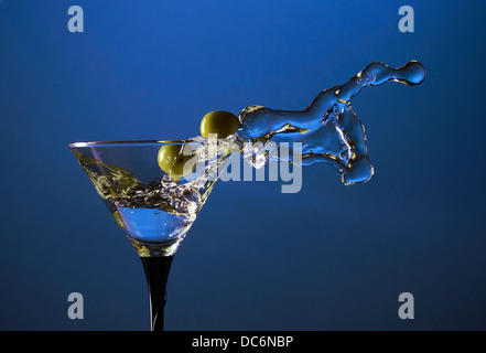 Glas mit Martini und grüne Oliven auf blauem Hintergrund Stockfoto