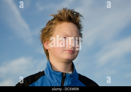 Porträt eines Teenagers mit stacheligen Haaren gegen blauen Himmel Stockfoto