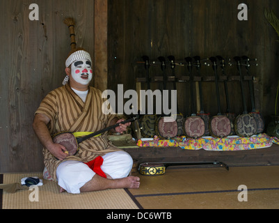 Okinawa Mann verkleidet als Chondara Clown mit Sanshin auf Ryukyu Mura ein historisches Dorf in Yomitan, Okinawa, Japan Stockfoto