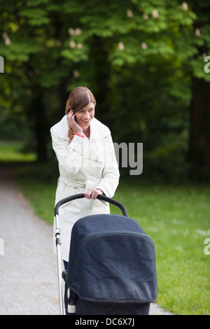 Niederlande. Haag, Mutter mit Kinderwagen im Park telefonieren mit Handy Stockfoto