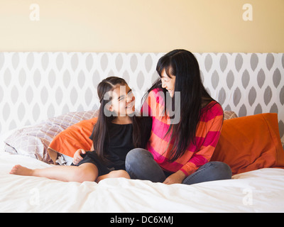 Mutter mit Tochter (8-9) sitzt auf Bett Stockfoto