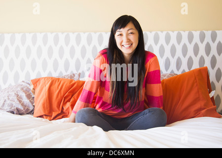 Porträt von Mitte Erwachsene Frau sitzt auf Bett Stockfoto