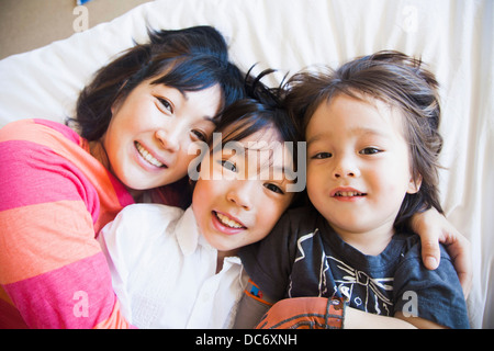Mutter mit Kindern auf Bett kuscheln Stockfoto
