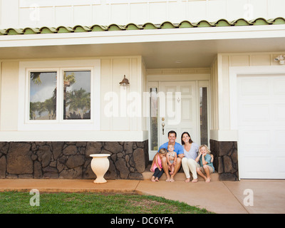 USA, Hawaii, Kauai, Familie mit drei Kindern (6-7, 2-3, 6-11 Monate) sitzt vor Haus Stockfoto