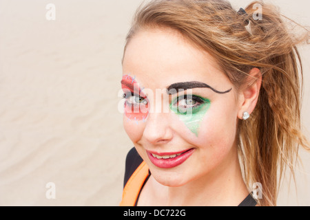 Ein close-up Kopfschuss von einem jungen weiblichen Zirkuskünstler mit Clown Make-up lächelnd und blickte in die Kamera. Stockfoto