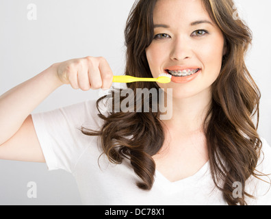 Schöne asiatische amerikanische Mädchen mit weißen T-shirt und kieferorthopädische Zahnspange Zähne putzen Stockfoto