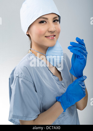 Weibliche Medic tragen scheuert sich chirurgische Kappe und Maske Stockfoto