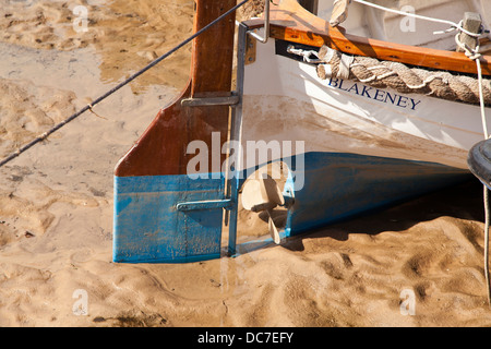 Ein Boot in Blakeney, Norfolk, England, das bei Ebbe auf dem Sand ruht. Stockfoto