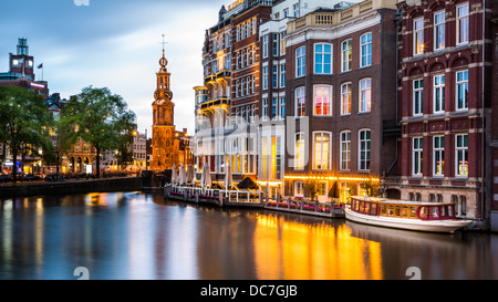 Amsterdam-Blick in der Abenddämmerung, mit typisch holländischen Häuser spiegelt sich in einem Kanal und dem Münzerturm Wahrzeichen im Hintergrund Stockfoto