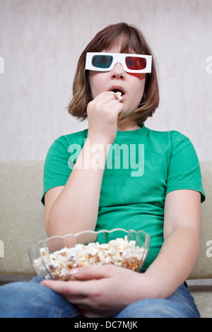 Mädchen TV Filme in Stereo-Anaglyphenbrille und Essen popcorn Stockfoto